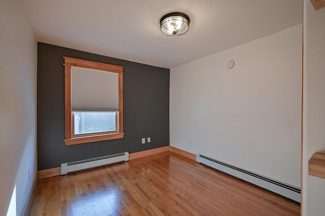 unfurnished room with a baseboard heating unit and light wood-type flooring