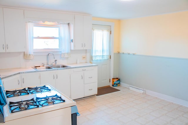 kitchen with white gas range, white cabinetry, and sink