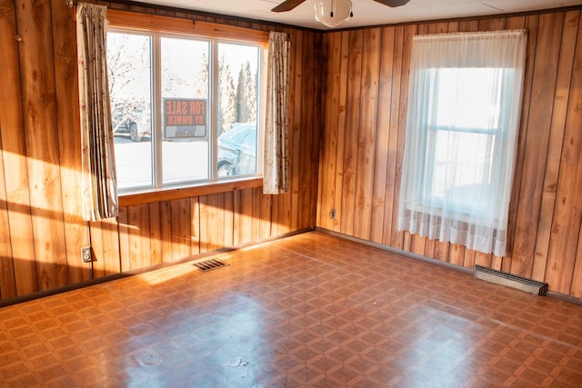 unfurnished room featuring ceiling fan and wood walls