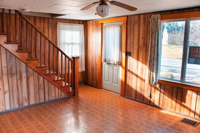 foyer with ceiling fan and wooden walls