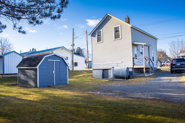 rear view of property featuring a lawn and a storage unit