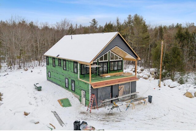 snow covered back of property with a forest view