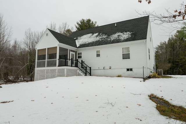 snow covered property with cooling unit and a sunroom