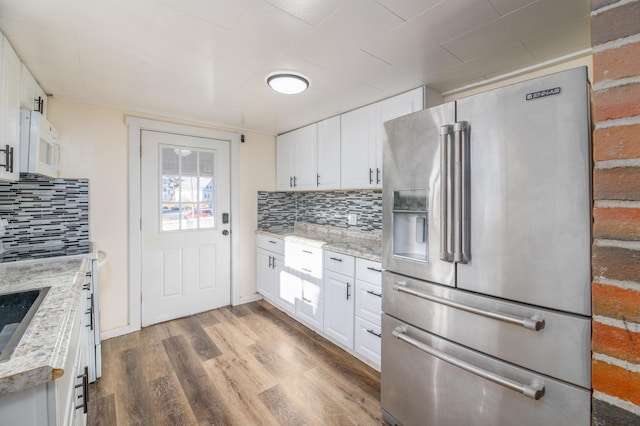 kitchen with hardwood / wood-style floors, high end fridge, light stone counters, and white cabinetry