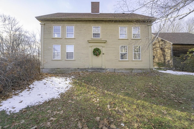 snow covered rear of property featuring a lawn