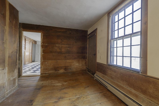 hallway with baseboard heating, wood-type flooring, and a healthy amount of sunlight