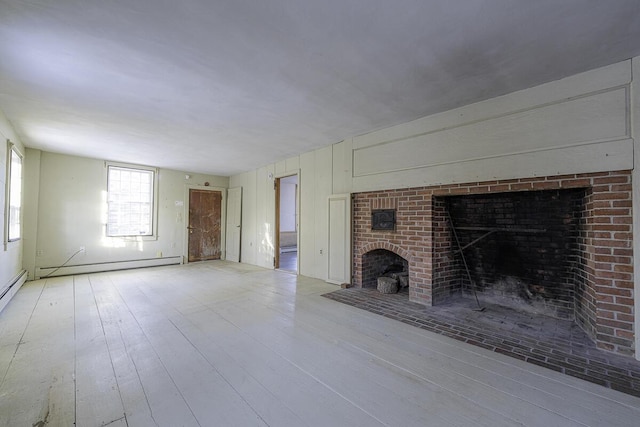 unfurnished living room with light wood-type flooring, a fireplace, and a baseboard radiator