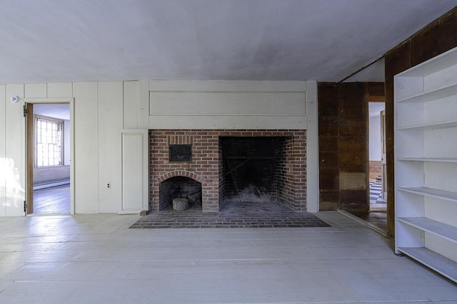 unfurnished living room with a brick fireplace and built in shelves