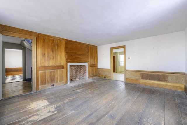 unfurnished living room featuring a baseboard heating unit and dark wood-type flooring