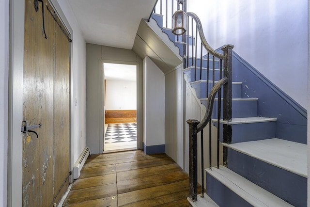 stairway with a baseboard heating unit and hardwood / wood-style floors