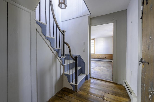 stairs featuring baseboard heating and hardwood / wood-style floors