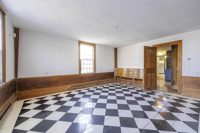 empty room featuring baseboard heating and wood walls