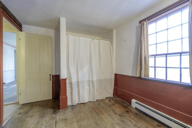 unfurnished room featuring baseboard heating and wood-type flooring