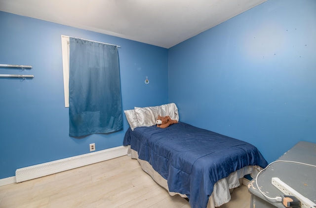 bedroom featuring light wood-type flooring and a baseboard heating unit