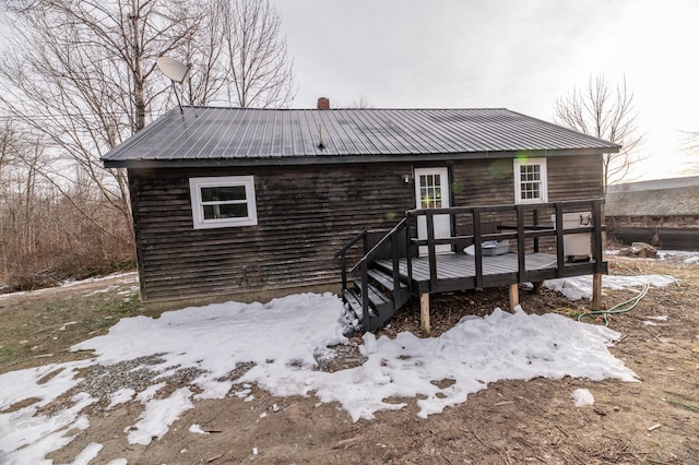 snow covered rear of property with a deck