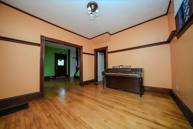 empty room with vaulted ceiling, light hardwood / wood-style flooring, and ornamental molding