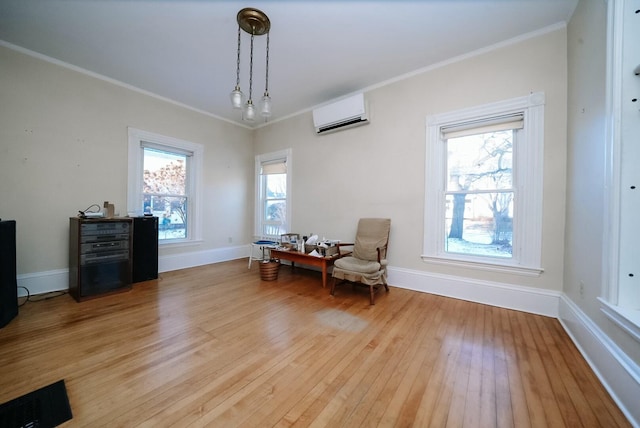 living area with a wall mounted AC, crown molding, plenty of natural light, and light hardwood / wood-style floors