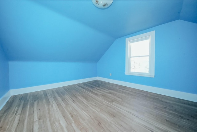 additional living space featuring light hardwood / wood-style floors and vaulted ceiling