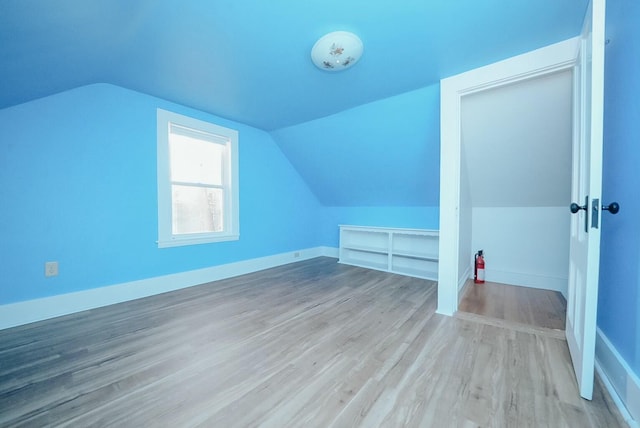 bonus room with light wood-type flooring and vaulted ceiling