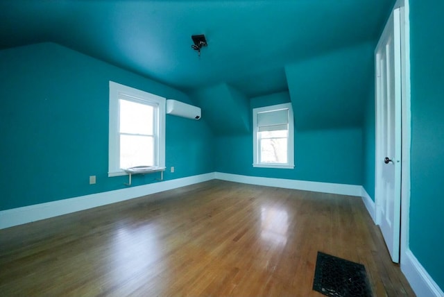 bonus room featuring a wall unit AC, hardwood / wood-style floors, and vaulted ceiling