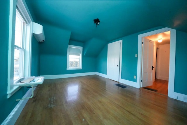 bonus room with hardwood / wood-style floors, lofted ceiling, and a wall mounted AC