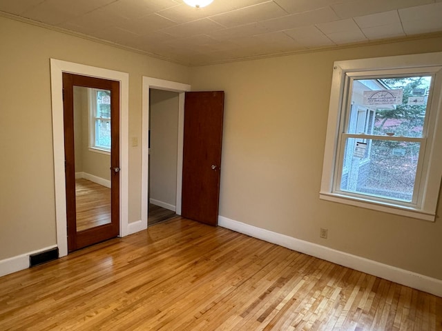 spare room featuring light wood-type flooring and ornamental molding