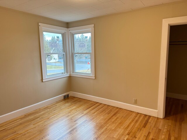 unfurnished bedroom featuring light wood-type flooring, ornamental molding, and a closet