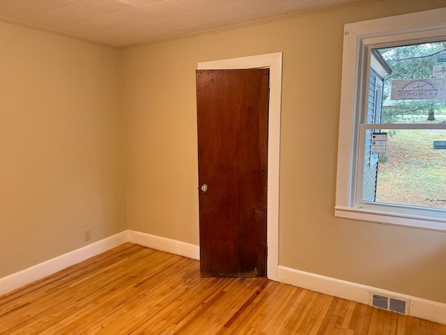 spare room with ornamental molding and light wood-type flooring