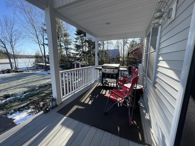 snow covered deck featuring grilling area and covered porch