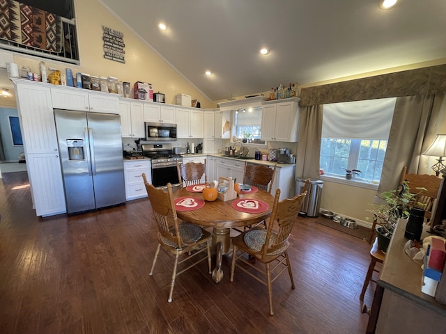 dining room with plenty of natural light, dark hardwood / wood-style floors, sink, and high vaulted ceiling