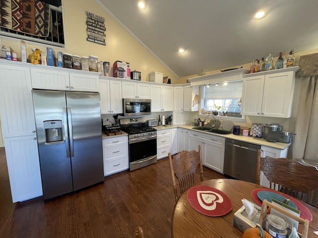 kitchen with dark wood-type flooring, white cabinets, sink, vaulted ceiling, and appliances with stainless steel finishes