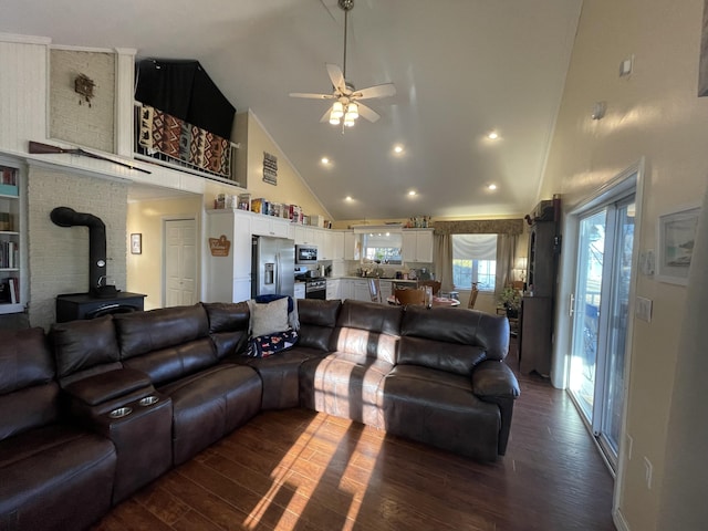 living room with dark hardwood / wood-style flooring, high vaulted ceiling, a wood stove, and ceiling fan