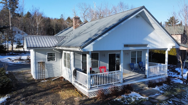 snow covered back of property with covered porch