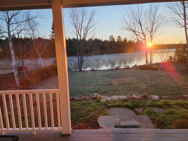 yard at dusk with a patio area and a water view