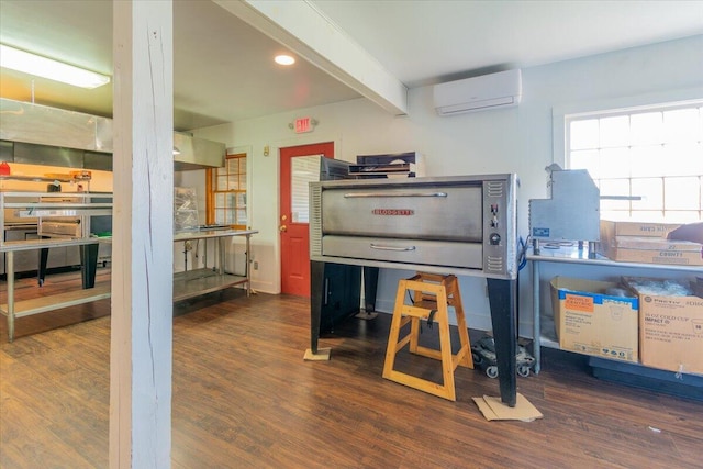 kitchen featuring dark hardwood / wood-style floors, beam ceiling, and a wall mounted AC