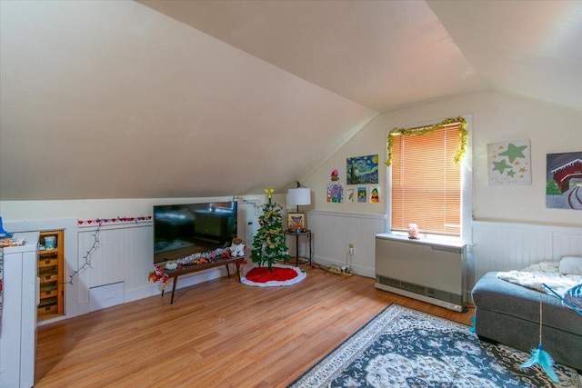 bedroom with radiator heating unit, vaulted ceiling, and hardwood / wood-style flooring