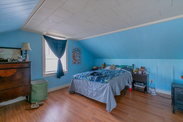 bedroom featuring wood-type flooring, vaulted ceiling, and ornamental molding