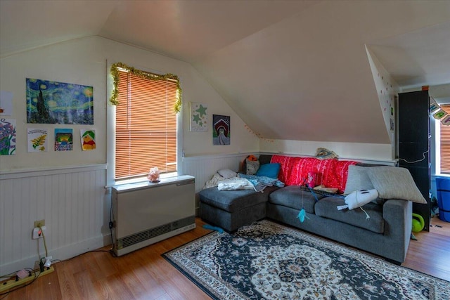 living room with heating unit, wood-type flooring, and vaulted ceiling