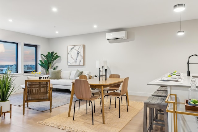 dining room with sink, a wall unit AC, and light hardwood / wood-style flooring