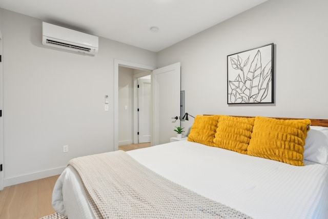 bedroom featuring light hardwood / wood-style floors and an AC wall unit