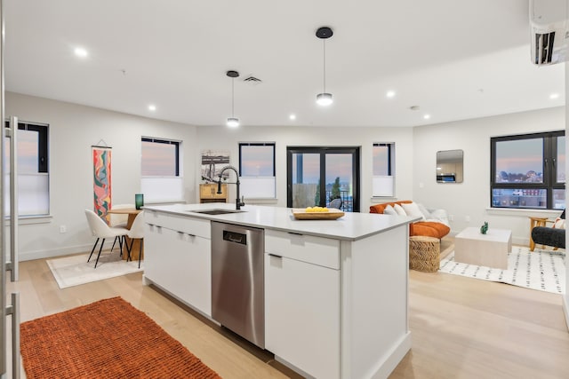 kitchen with white cabinetry, sink, stainless steel dishwasher, decorative light fixtures, and a kitchen island with sink