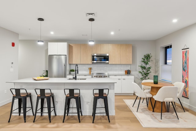 kitchen with appliances with stainless steel finishes, white cabinetry, pendant lighting, and sink