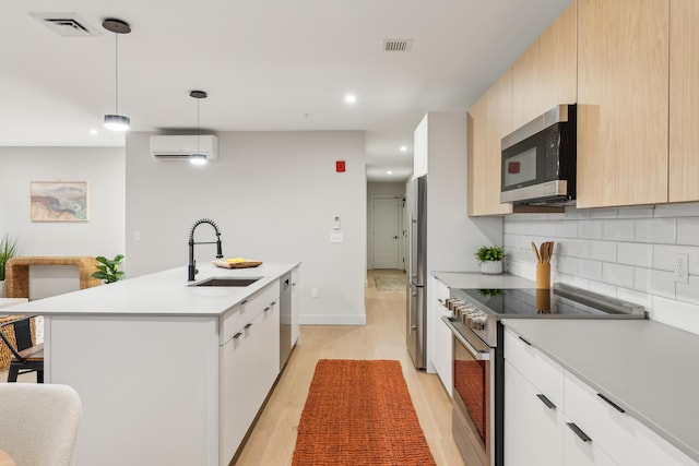 kitchen with sink, stainless steel appliances, backsplash, decorative light fixtures, and a kitchen island with sink