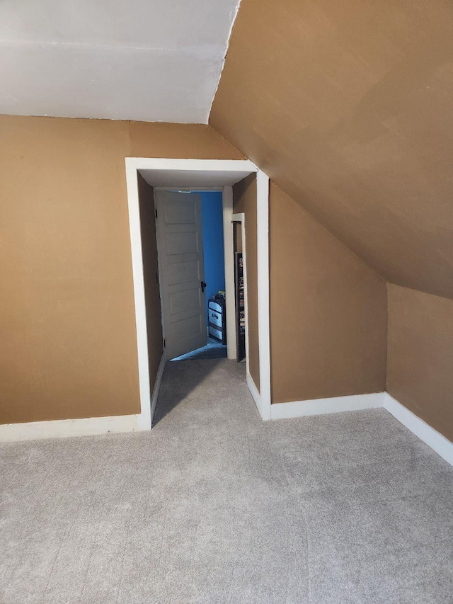 additional living space with light colored carpet and vaulted ceiling