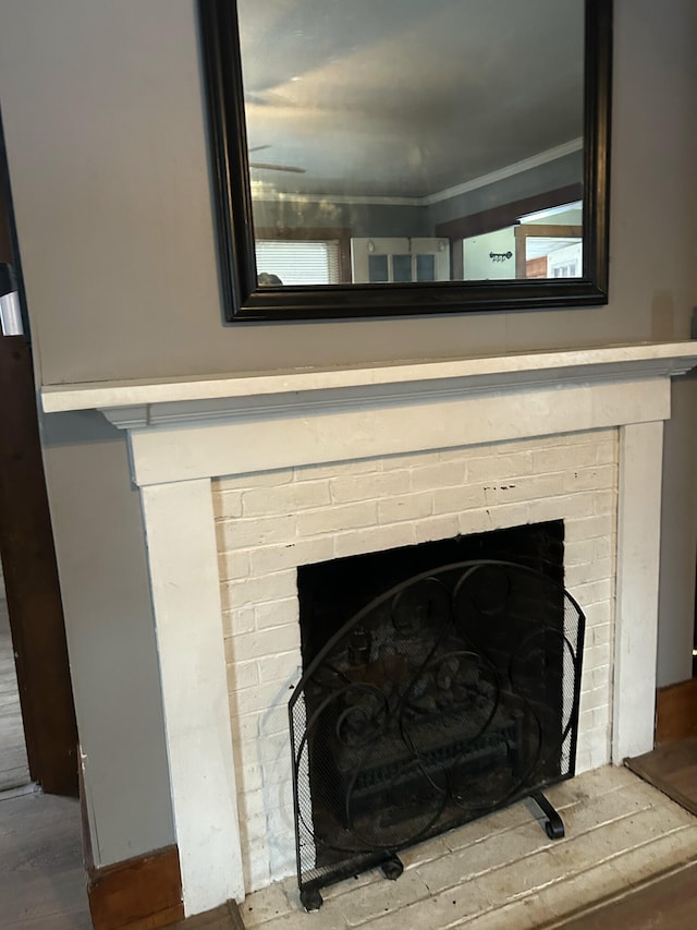 room details featuring wood-type flooring, crown molding, and a brick fireplace