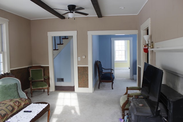 sitting room featuring ceiling fan, beamed ceiling, and light colored carpet