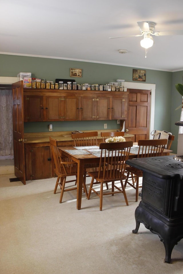 dining room with ceiling fan, light colored carpet, and ornamental molding