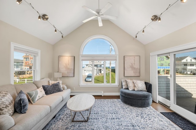 living room featuring hardwood / wood-style floors, lofted ceiling, ceiling fan, baseboard heating, and plenty of natural light