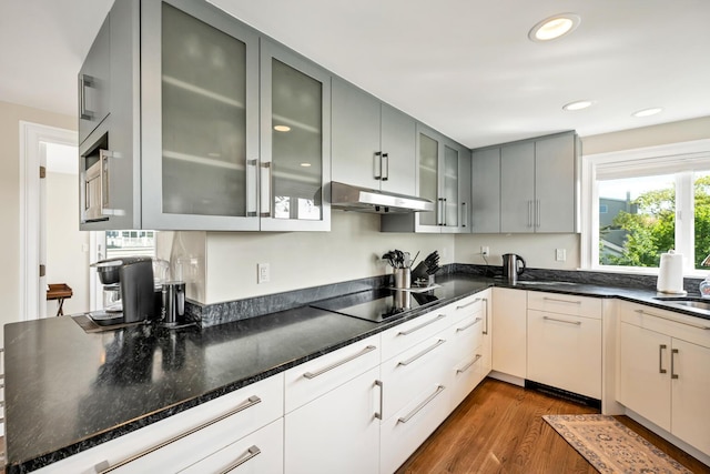 kitchen featuring sink, dark wood-type flooring, dark stone countertops, gray cabinets, and black electric stovetop