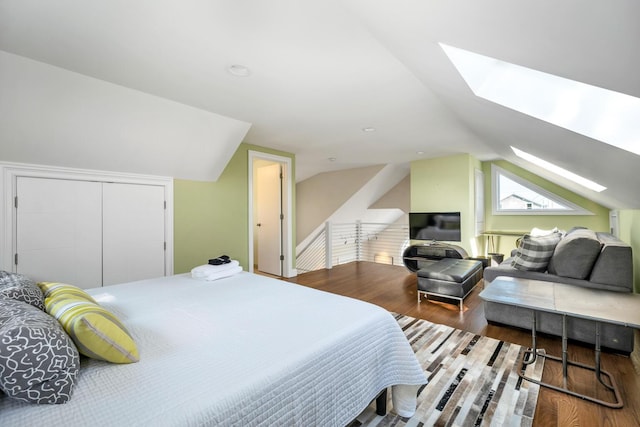 bedroom with a closet, hardwood / wood-style floors, and vaulted ceiling with skylight